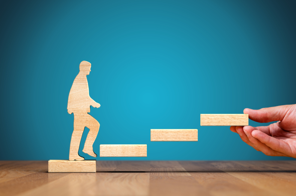 Image of a wooden man climbing wooden steps.