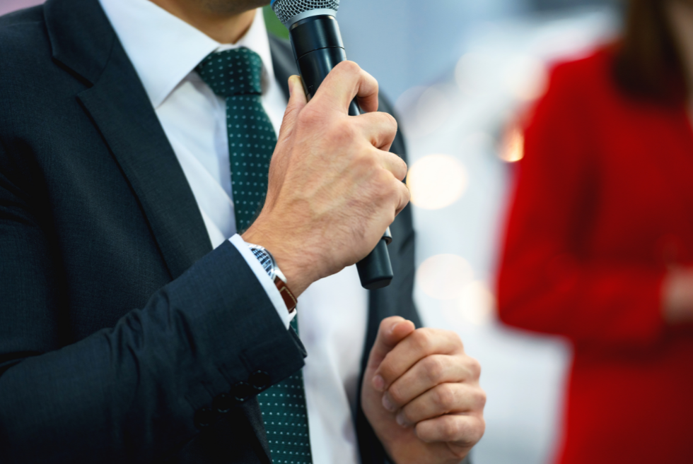 Close up of a man in a suit holding a microphone.